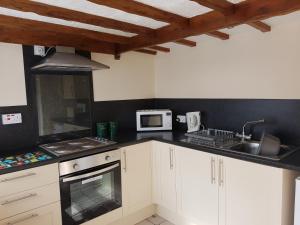 a kitchen with white cabinets and a sink at Holly Cottage in Burgh le Marsh