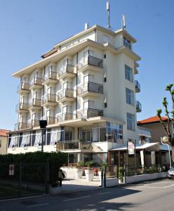 a large white building with balconies on a street at Hotel Goldene Rose in Rimini