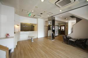 伊势崎市伊势崎收获经济型酒店的一个带椅子和桌子的空的大堂