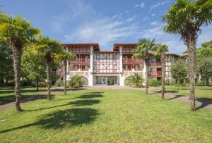 an exterior view of a building with palm trees at Residence Le Domaine de Gascogne - maeva Home in Biscarrosse
