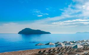 a group of beach chairs and umbrellas on a beach at Porto Platanias Beach Resort & Spa in Plataniás