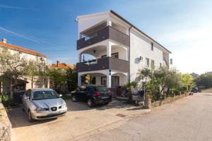 a house with two cars parked in front of it at Apartments Hajl in Krk