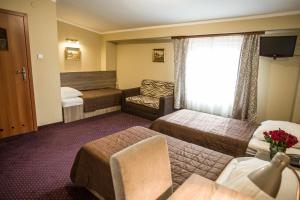 a hotel room with two beds and a couch at Hotel Maksymilian in Krakow