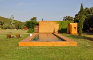 een vijver in het midden van een tuin met twee stoelen bij Hotel Fundació L'Olivar in Ventalló