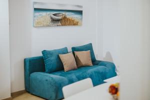 un sofá azul en una sala de estar con una pintura en Stephanie Studios en Lárnaca