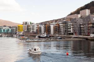 un pequeño barco en un cuerpo de agua con edificios en BJØRVIKA APARTMENTS, Damsgård Area, Bergen city center, en Bergen