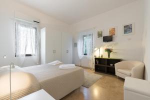 a white bedroom with a bed and a chair at Roommo San Iacopino in Florence