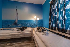 two beds in a room with a sailboat in the ocean at Apartments Faro & Mondo in Crikvenica