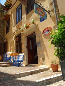 a building with blue chairs in front of a door at Anemones Rooms in Chania