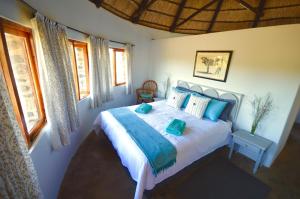 a bedroom with a large bed with blue pillows at Swartkop Cottage in Winterton
