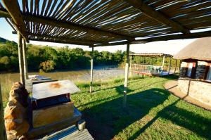 an outdoor grill under a wooden pergola at Swartkop Cottage in Winterton