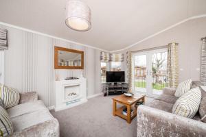 a living room with a couch and a tv at Thistle Lodge in Auchterarder