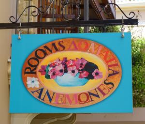Ein Schild hängt an einem Gebäude mit Blumen drauf. in der Unterkunft Anemones Rooms in Chania