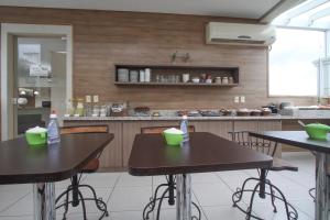 zwei Tische in einer Küche mit grünen Schüsseln darauf in der Unterkunft Hotel Hola in Florianópolis