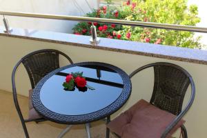 a table and chairs with flowers on a balcony at Rooms Nadia3 in Baška