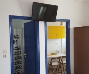 a room with a table and a tv on a wall at Helios Hotel in Agia Marina Aegina