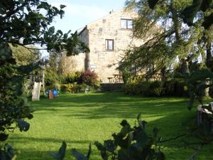オールストンにあるWest Nattrass Guest Houseの芝生の大きな石造りの家がある大庭