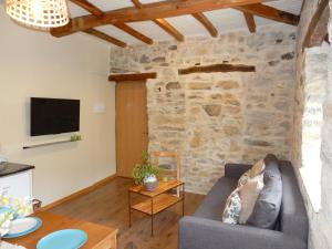 a living room with a couch and a stone wall at Apartamento Las Medulas in Covas
