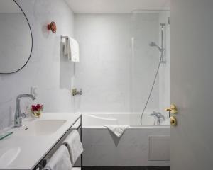 biała łazienka z wanną i umywalką w obiekcie Hotel Malte - Astotel w Paryżu