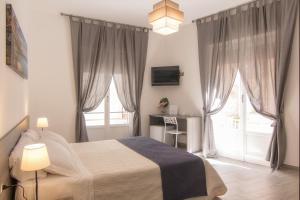 ein Schlafzimmer mit einem Bett und zwei Fenstern in der Unterkunft Cavour Rooms in Syrakus