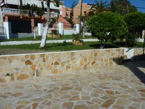 a stone wall next to a tree and a sidewalk at Spiti Anna Maria in Corfu