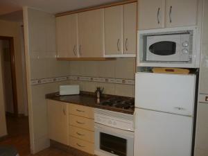 a kitchen with a white refrigerator and a microwave at Soling 103 in La Manga del Mar Menor