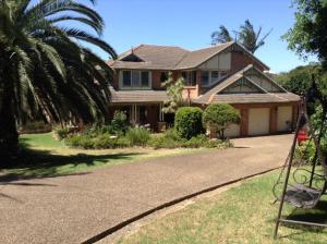 a house with a palm tree in front of a driveway at Kiama Guesthouse in Kiama