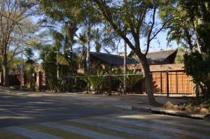 a street with a fence and a house with trees at Birrea Guest house in Polokwane