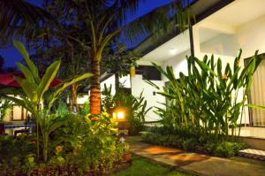 a garden with plants and a palm tree at night at Palm Garden Bali in Nusa Dua