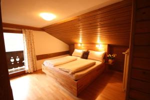 sypialnia z łóżkiem i drewnianą ścianą w obiekcie Appartement Schmiedhof w mieście Zell am See