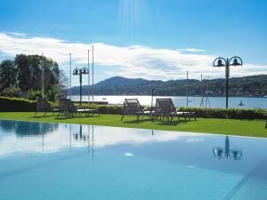 uma piscina com espreguiçadeiras junto a um lago em Seehotel Engstler em Velden am Wörthersee