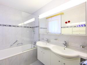 a bathroom with a sink and a tub and a mirror at Brunnmatt Holiday Apartment Zermatt in Zermatt