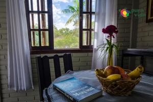 a book and a basket of fruit on a table at Pura Vida Residence in Morretes