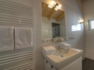 biała łazienka z umywalką i lustrem w obiekcie Residenz Kitzsteinhornblick by Kaprun Rentals w Kaprunie