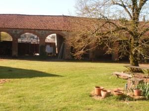 un edificio de ladrillo con un árbol y algunas ollas en la hierba en Le Logis, en Les Pineaux