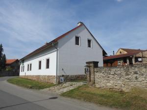 une maison blanche avec un mur en pierre à côté d'une rue dans l'établissement Restaurace a penzion U Lva, à Karlštejn