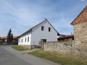 a white building with a stone wall next to a street at Restaurace a penzion U Lva in Karlštejn