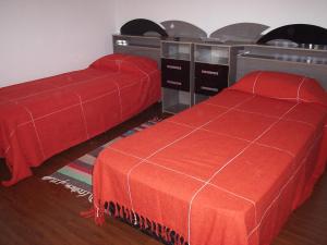 a bedroom with two beds with red covers and a table at Pousada Canto da Maritaca in Resende Costa