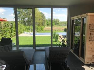 a screened in porch with chairs and a view of a yard at Alwine - Landhaus an den Spreewiesen in Rietz Neuendorf