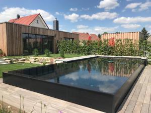 a swimming pool in a garden with a house at Alwine - Landhaus an den Spreewiesen in Rietz Neuendorf