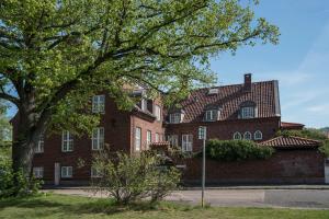 un grand bâtiment en briques avec un arbre devant lui dans l'établissement Halmstad Hotell & Vandrarhem Kaptenshamn, à Halmstad
