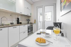 a white kitchen with a table with a glass of orange juice at Santa Catarina l by An Island Apart in Funchal +13 photos