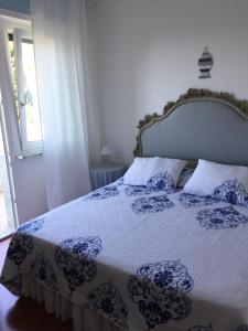 Schlafzimmer mit einem Bett mit einer blauen und weißen Bettdecke in der Unterkunft L`attico di Anna in Sanremo