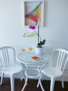 una mesa de cristal con tres sillas blancas y una flor en ella en Deslumbrante vista para a Praia de Copacabana., en Río de Janeiro