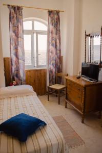a bedroom with two beds and a desk and a window at Hotel Angelino in Ischia