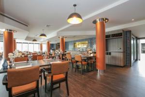 ein Restaurant mit orangefarbenen Säulen, Tischen und Stühlen in der Unterkunft Fletcher Hotel-Restaurant Leidschendam – Den Haag in Leidschendam