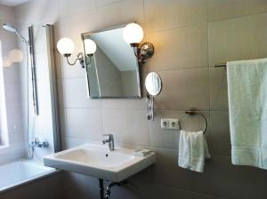a bathroom with a sink and a mirror and a tub at Reetdachhaus Strandecke in Freest
