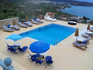 a swimming pool with blue chairs and umbrellas at Epidavros Seascape in Ancient Epidauros