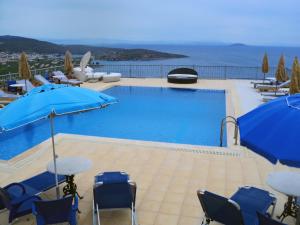 een zwembad met blauwe parasols en stoelen bij Epidavros Seascape in Oud Epidauros