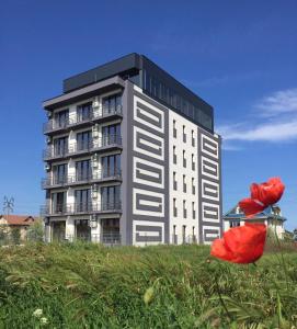 Un grand bâtiment avec des fleurs rouges devant lui dans l'établissement Hotel Sweet, à Mamaia Nord – Năvodari